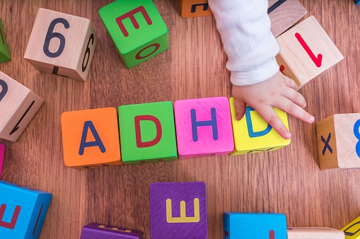 kostki z literami dla dzieci, ułożone w imię ADHD, z ręką dziecka