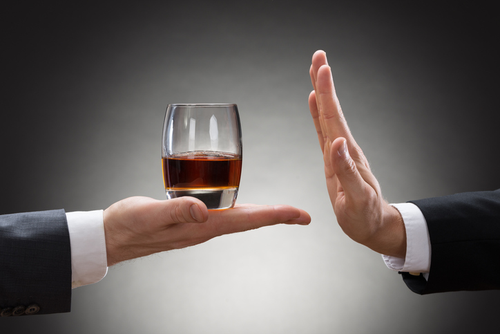 Napoje alkoholowe są główną przyczyną wrzodów żołądka. W przypadku wrzodów żołądka przyspieszają pęknięcie wrzodu i krwawienie. Źródło: Getty Images dłoń osoby trzyma szklankę alkoholu, a dłoń innej osoby ją odrzuca