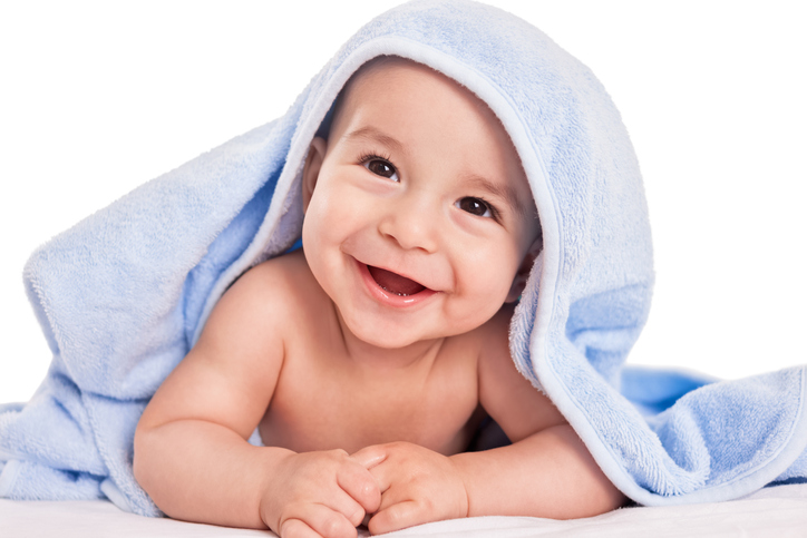Ważne jest, aby od czasu do czasu pozwolić skórze dziecka swobodnie oddychać. Źródło: Thinkstock śmiejące się dziecko na brzuszku, przykryte ręcznikiem
