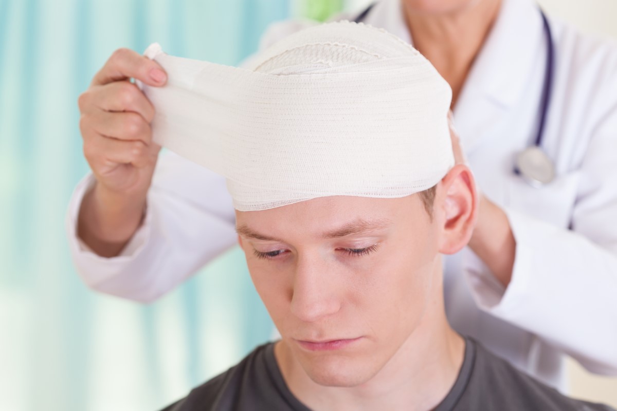 Po urazie głowy ważne jest monitorowanie stanu i pojawienia się problemów zdrowotnych. Źródło: Getty Images Ból głowy po wypadku, zabandażowana głowa, lekarz leczy chłopca z urazem głowy