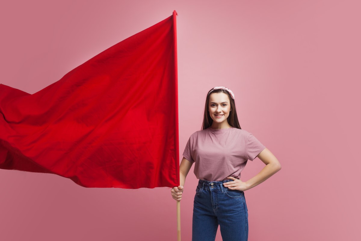 Kobieta trzyma dużą czerwoną flagę jako ostrzeżenie.