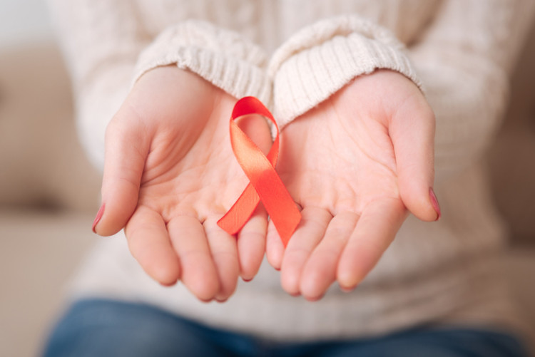 Czerwona wstążka jako symbol walki z AIDS. Źródło: Getty Images czerwona wstążka w rękach kobiety