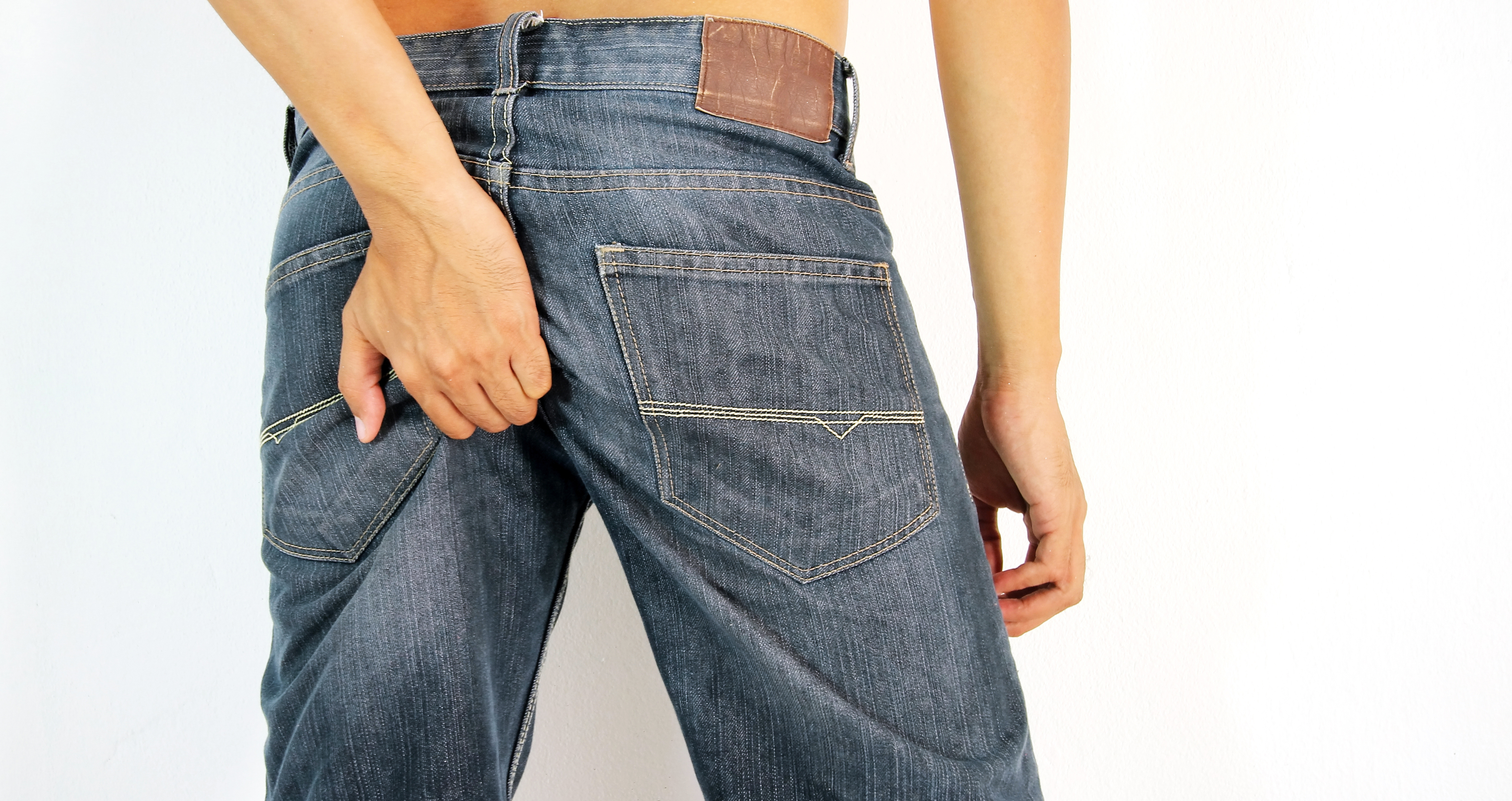 Najczęstszą drogą przenoszenia wirusowego zapalenia jelit jest transmisja fekalno-oralna (odbyt-usta). Zdjęcie: Thinkstock mężczyzna w dżinsach drapiący się po tyłku