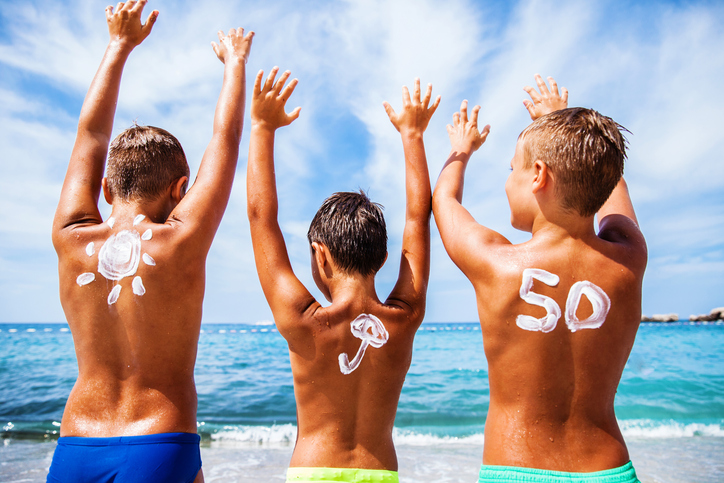 W dzieciństwie wybieramy SPF 50 i 50+. Źródło: Thinkstock Krem przeciwsłoneczny dla dzieci z OF 50, dzieci są na plaży nad morzem i dobrze się bawią, ich ręce są w górze
