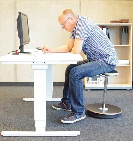 Mężczyzna siedzi przy biurku, ma siedzącą pracę