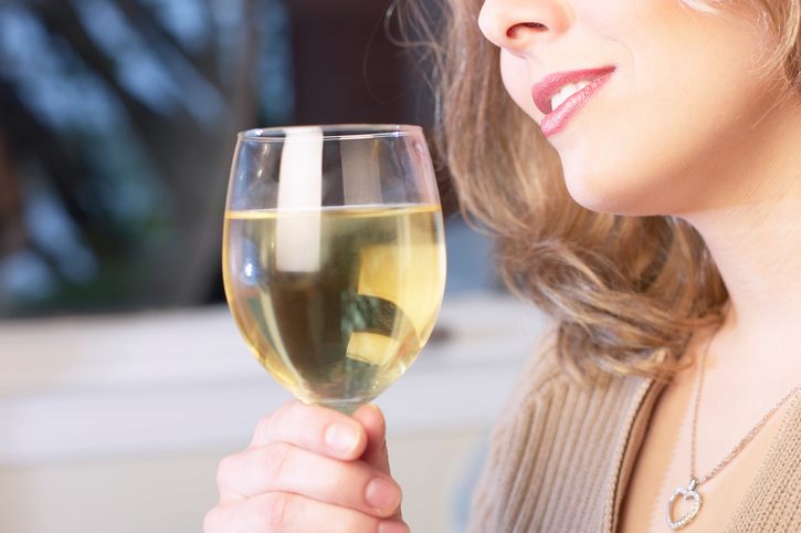 Alkoholizm jest przyczyną wielu chorób układu pokarmowego. Źródło zdjęcia: Getty Images Kobieta pijąca alkohol, wino w kieliszku, wycięcie twarzy kobiety - nos i usta, trzymająca kieliszek. Długotrwały alkoholizm jako przyczyna zaburzeń połykania